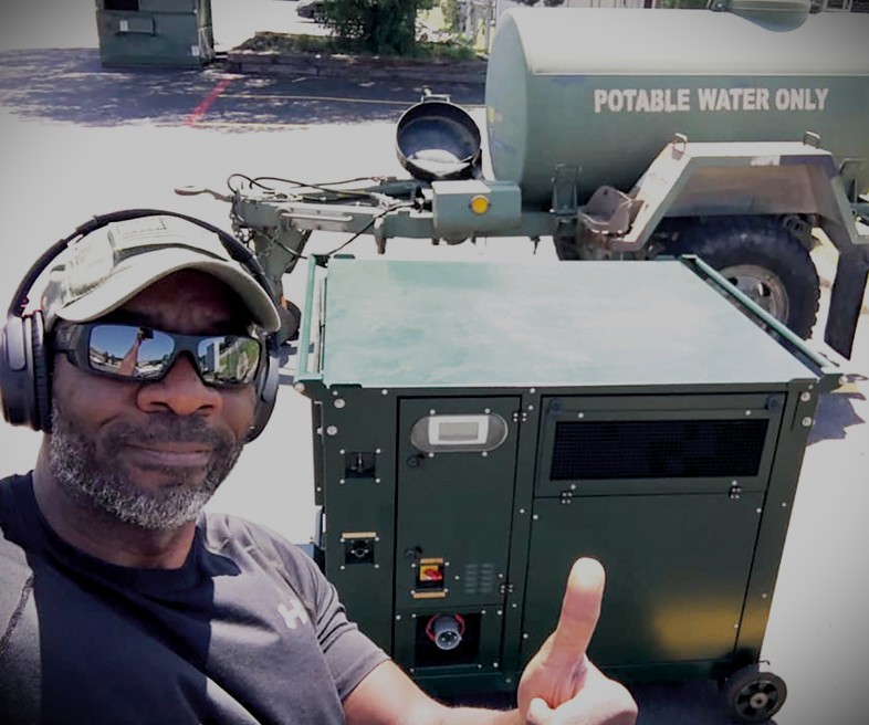 Moses West beside atmospheric water generation equipment and a potable water tank