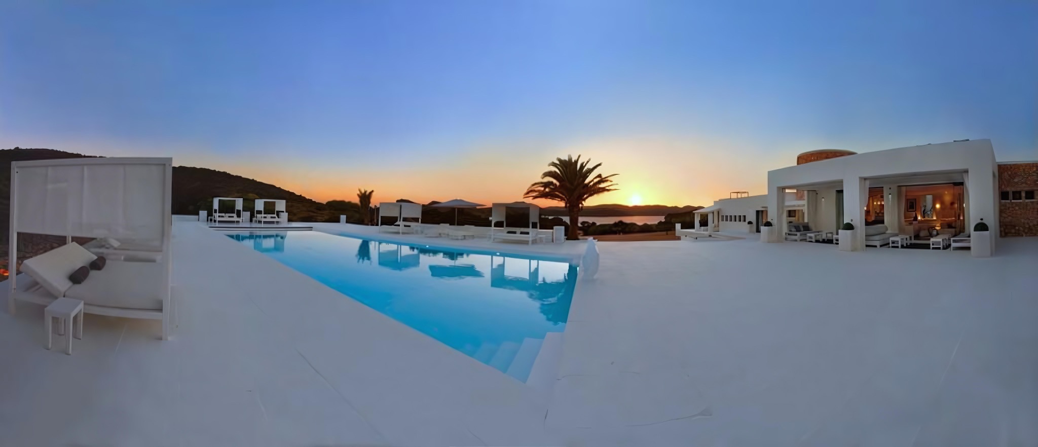 Wide pool terrace and Tagomago villa at sunset